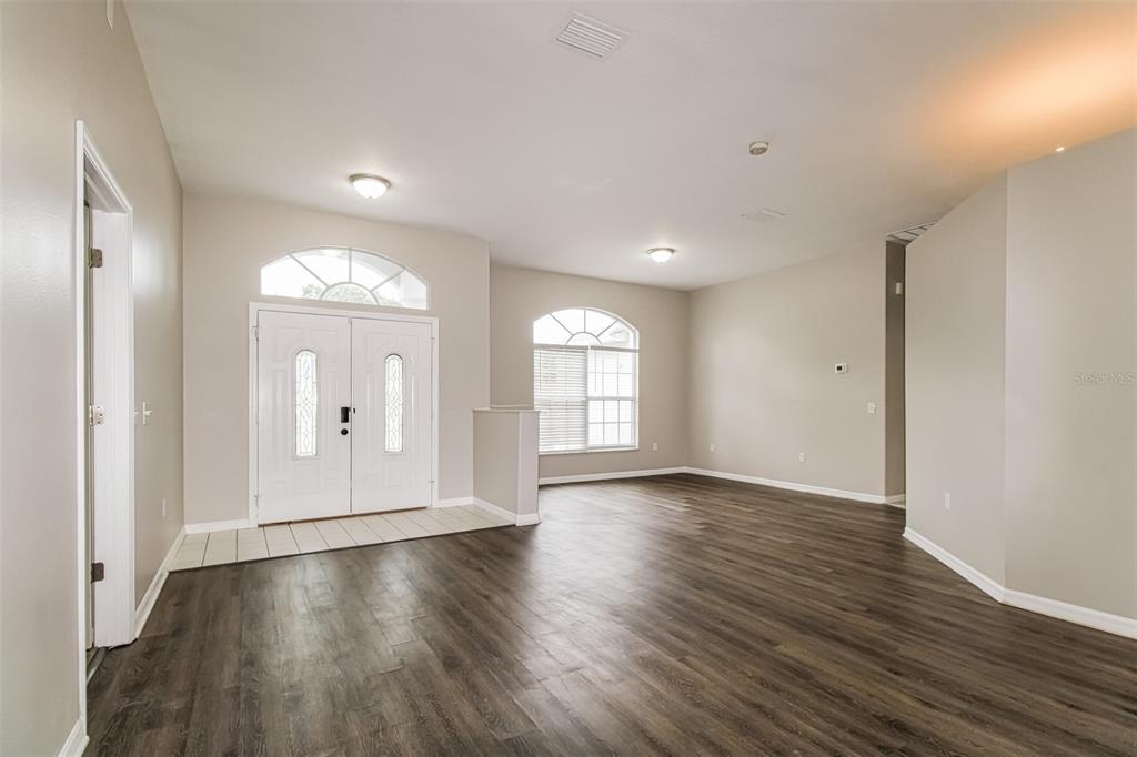 A bright entryway features double front doors, arched windows, and dark wood-look flooring — 4604 TRIMBLE LANE, NEW PORT RICHEY, FL