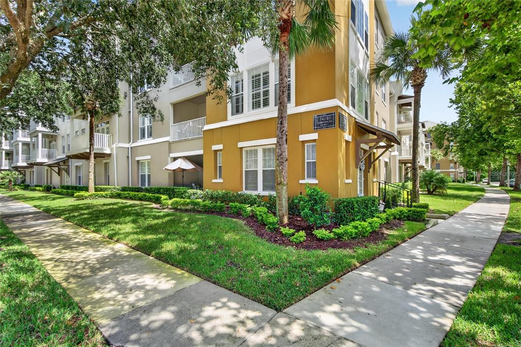 A multi-story apartment building with yellow stucco walls, white trim, and surrounding landscaping — 1411 CELEBRATION AVENUE UNIT 103, CELEBRATION, FL