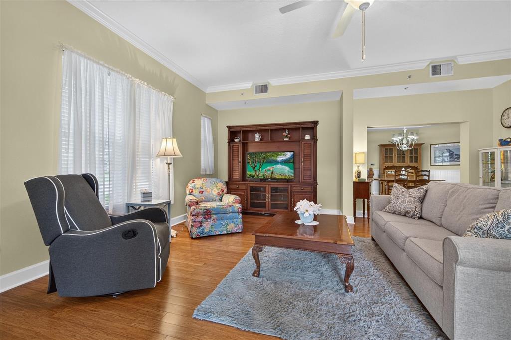 A living room features hardwood floors, a grey sofa, a floral armchair, and a media center — 1411 CELEBRATION AVENUE UNIT 103, CELEBRATION, FL