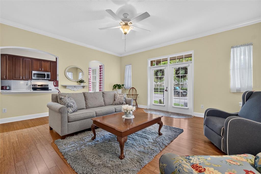 A living room with hardwood floors, a gray sofa, a coffee table, and a ceiling fan — 1411 CELEBRATION AVENUE UNIT 103, CELEBRATION, FL