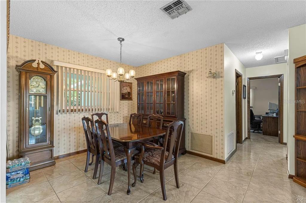 A dining room features a wooden table, chairs, a grandfather clock, and patterned wallpaper — 9140 SW 101ST LANE, OCALA, FL