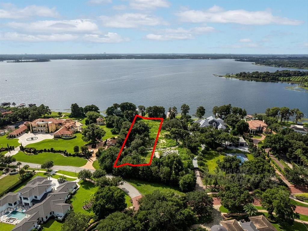 An aerial view shows a vacant, tree-covered lot outlined in red bordering a large lake — 12418 PARK AVENUE, WINDERMERE, FL