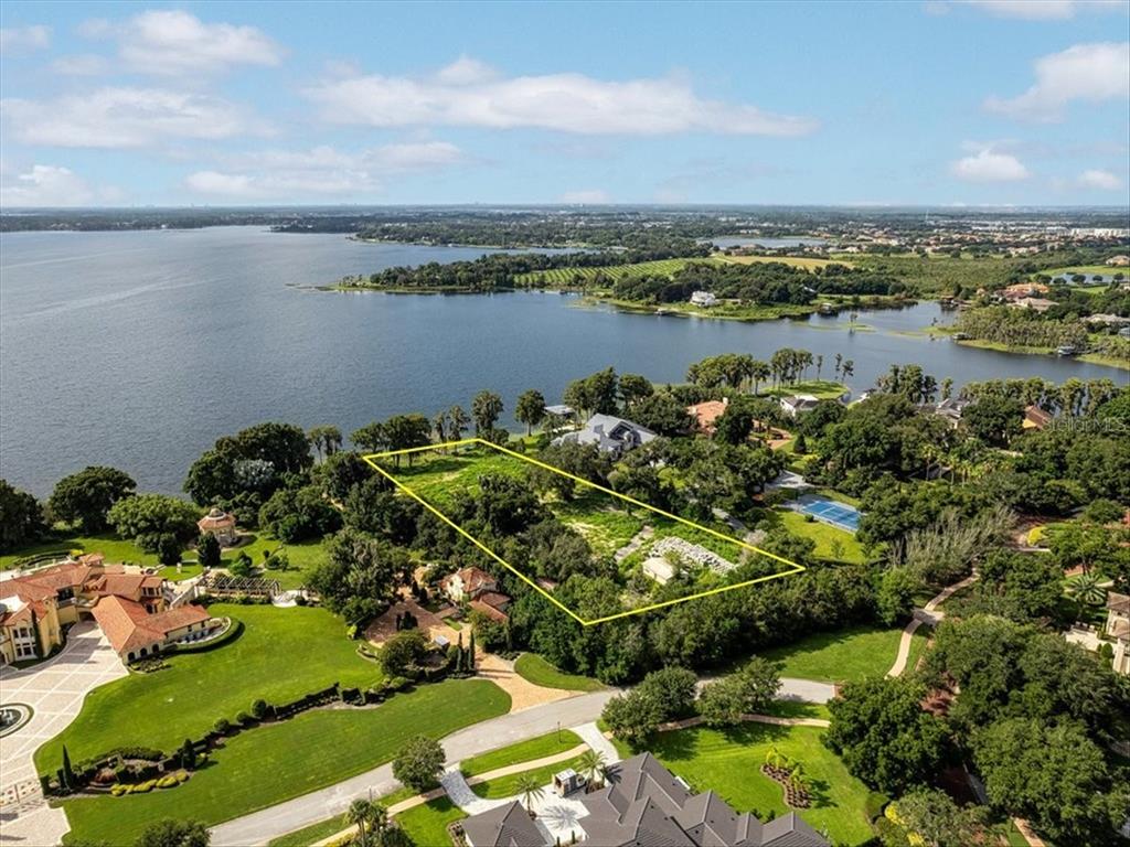 An aerial view shows a vacant, rectangular lot outlined in yellow near a large lake — 12418 PARK AVENUE, WINDERMERE, FL