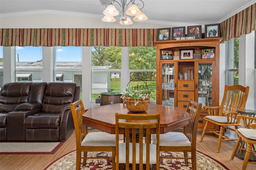 A dining area features an octagonal wooden table, chairs, and a hutch near large windows — 8084 LITTLE TEE LANE, BROOKSVILLE, FL