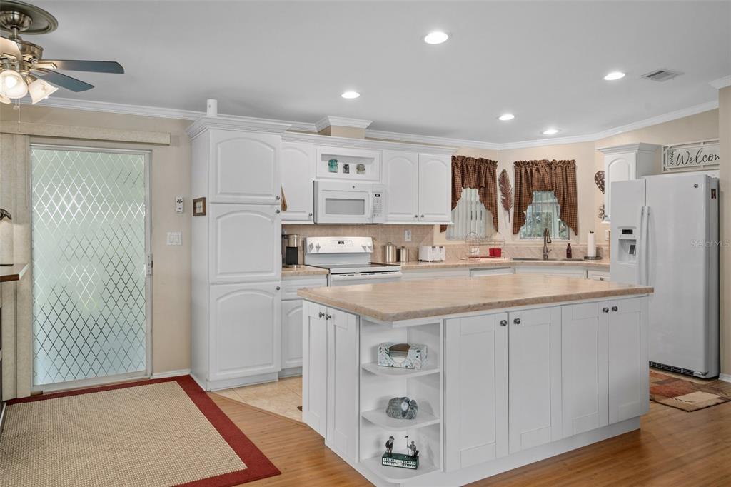 A kitchen with white cabinets, a central island, and light-colored countertops on wood flooring — 8084 LITTLE TEE LANE, BROOKSVILLE, FL