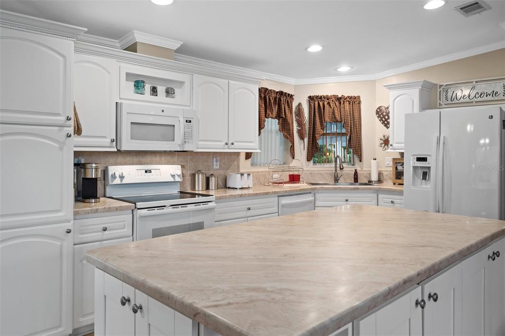 A kitchen features white cabinetry, a large island with a stone countertop, and white appliances — 8084 LITTLE TEE LANE, BROOKSVILLE, FL