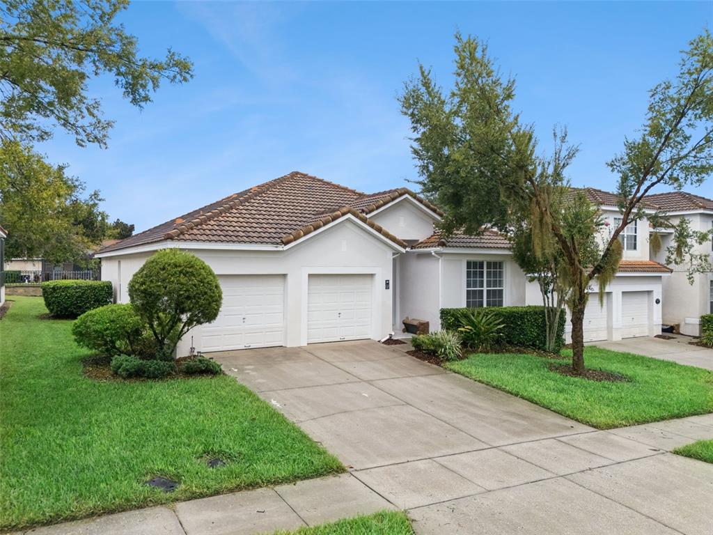 A single-story house with a two-car garage, a tiled roof, and a front lawn — 7747 TEASCONE BOULEVARD, KISSIMMEE, FL