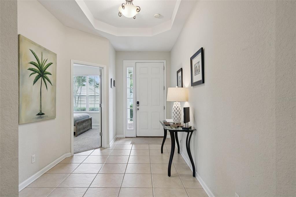 A tiled entryway features a white front door, a console table, and a palm tree painting — 7747 TEASCONE BOULEVARD, KISSIMMEE, FL