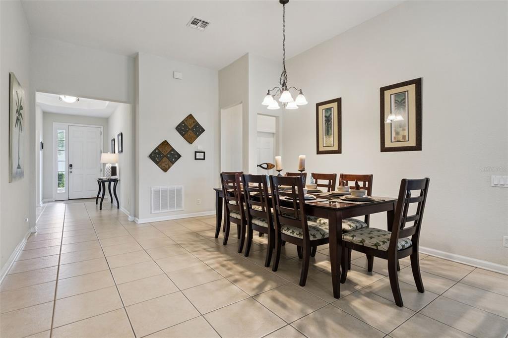 A dining room with a dark wood table, six chairs, and tile flooring — 7747 TEASCONE BOULEVARD, KISSIMMEE, FL