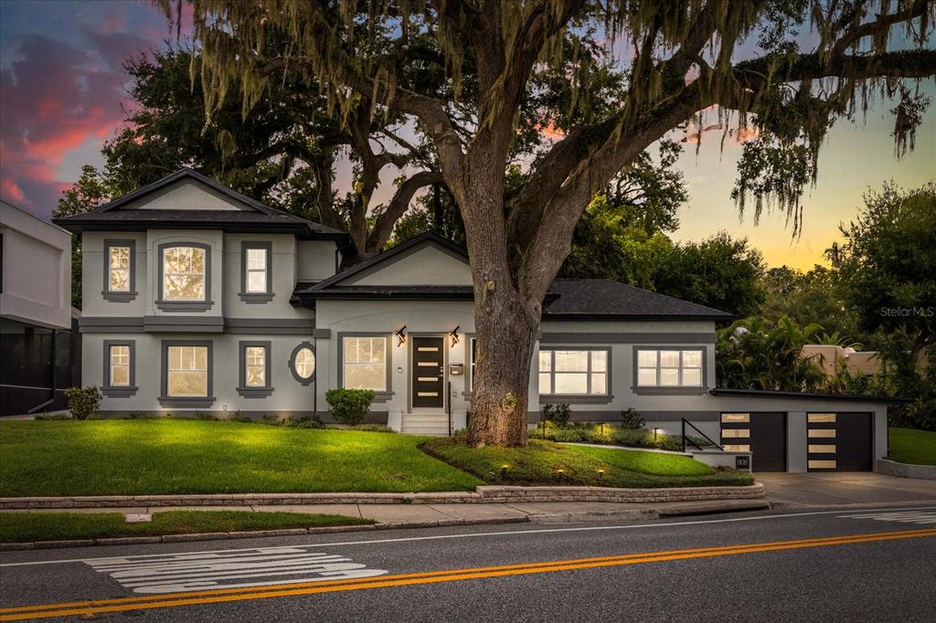 A two-story gray house with a large oak tree in the front yard at dusk — 808 EDGEWATER DRIVE, ORLANDO, FL