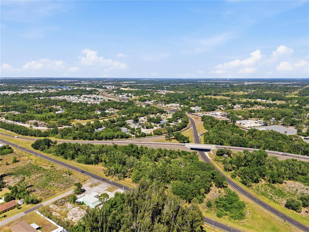 An aerial view shows a highway overpass surrounded by trees, residential areas, and open land — 4340 US 19, PALMETTO, FL