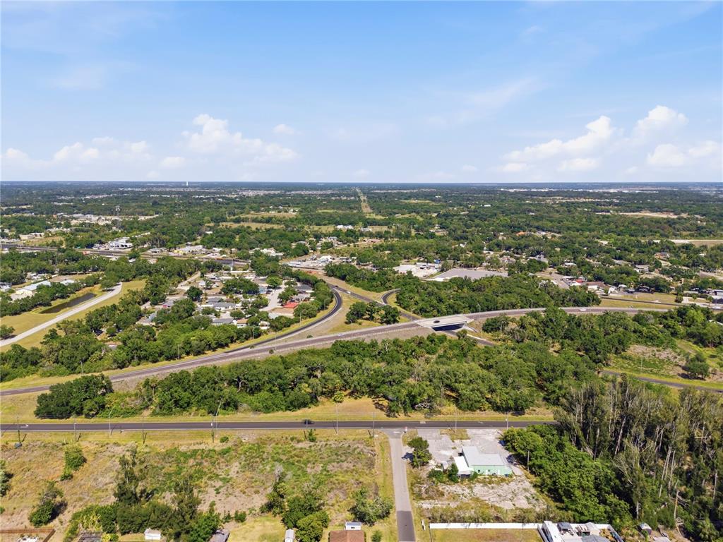 An aerial view shows a highway overpass, surrounding wooded areas, and scattered residential and commercial buildings — 4340 US 19, PALMETTO, FL