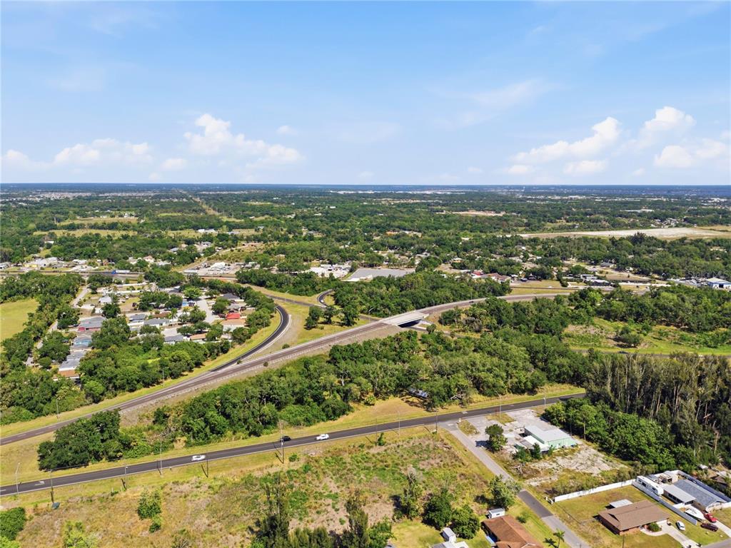 An aerial view shows a highway overpass, surrounding residential areas, and wooded land — 4340 US 19, PALMETTO, FL