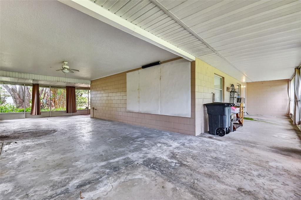 A large, covered concrete patio features a block wall, ceiling fan, and screened-in enclosure — 37320 BEACH DR, UMATILLA, FL