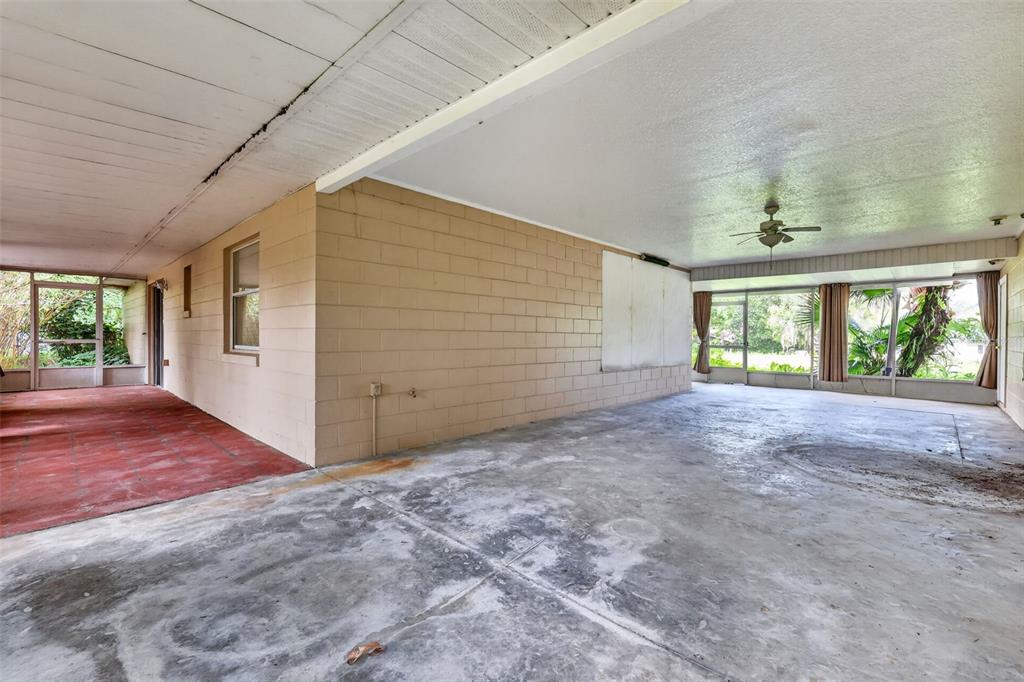 A large, covered concrete patio features a block wall, ceiling fan, and screened-in windows — 37320 BEACH DR, UMATILLA, FL