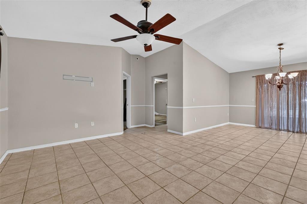 A living room with beige walls, tile flooring, a ceiling fan, and a dining area — 37320 BEACH DR, UMATILLA, FL