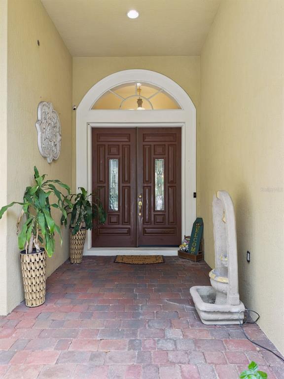 A covered entryway features a brick floor, double front doors, and a stone fountain — 2027 RICKOVER PLACE, WINTER GARDEN, FL