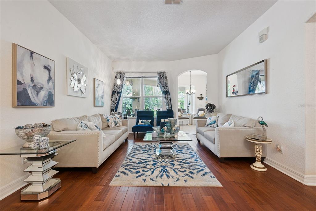 A living room features two beige sofas, blue accent chairs, and a patterned area rug — 2027 RICKOVER PLACE, WINTER GARDEN, FL