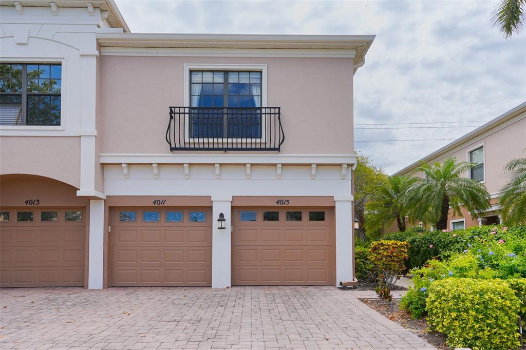 A two-story townhouse exterior features a paved driveway, two garage doors, and a small balcony — 4015 OVERTURE CIRCLE UNIT 314, BRADENTON, FL