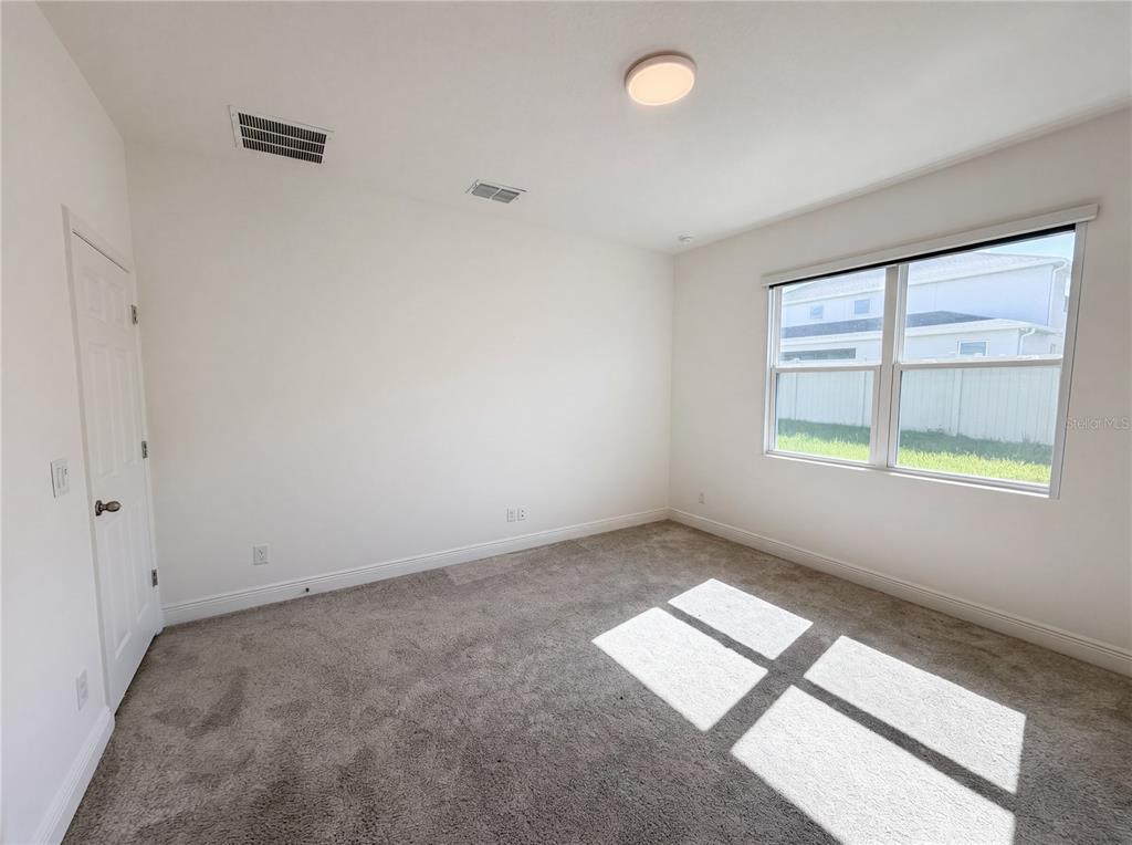 An empty bedroom features white walls, gray carpeting, a single window, and a ceiling light — 7725 SCICLI WAY, CLERMONT, FL