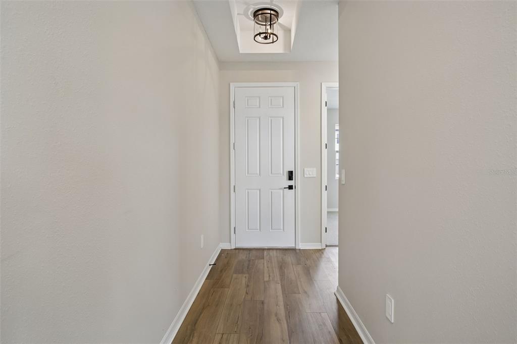 An empty room with light wood-look flooring, a chandelier, and sliding glass doors to water — 5969 FRESH FLORA DRIVE, WIMAUMA, FL