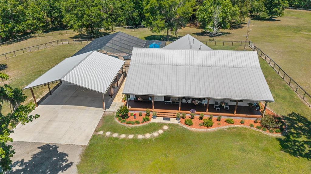 An aerial view shows a house with a metal roof, a carport, and a screened pool — 20005 NW 135TH AVENUE, MICANOPY, FL