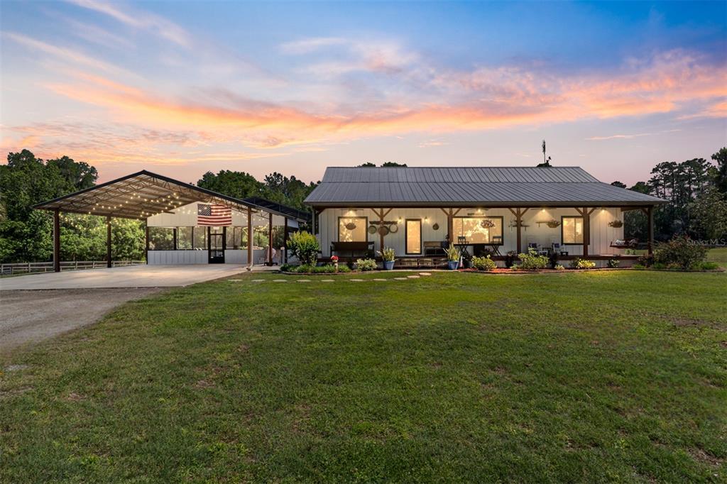 A single-story house with a metal roof, a front porch, and an attached open carport — 20005 NW 135TH AVENUE, MICANOPY, FL
