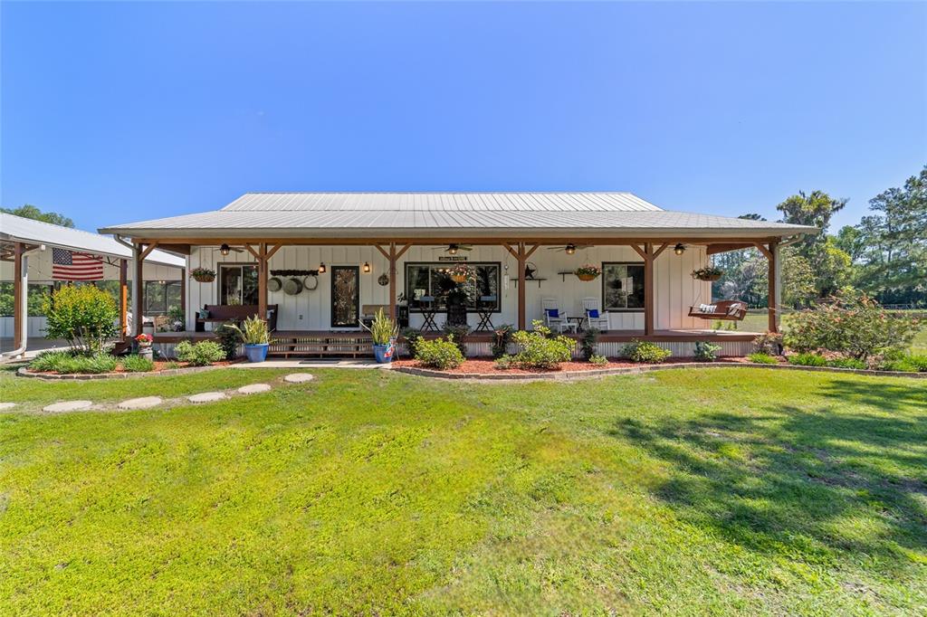 A single-story farmhouse with a metal roof and a wide covered front porch — 20005 NW 135TH AVENUE, MICANOPY, FL