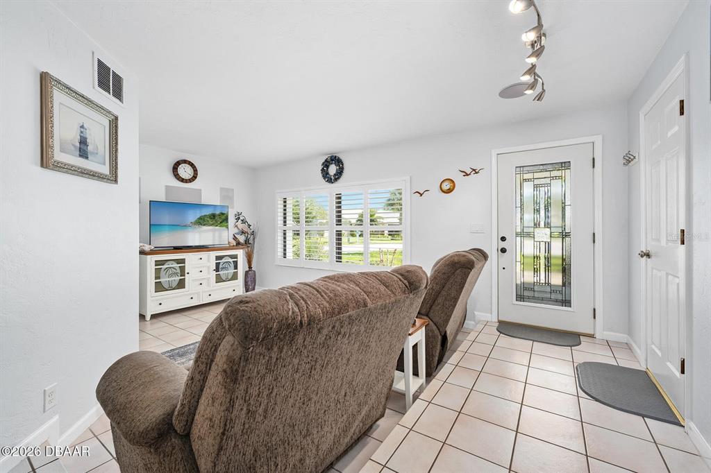 A living room features tile flooring, a brown recliner, a television, and a front door — 4708 DIXIE DRIVE, PONCE INLET, FL
