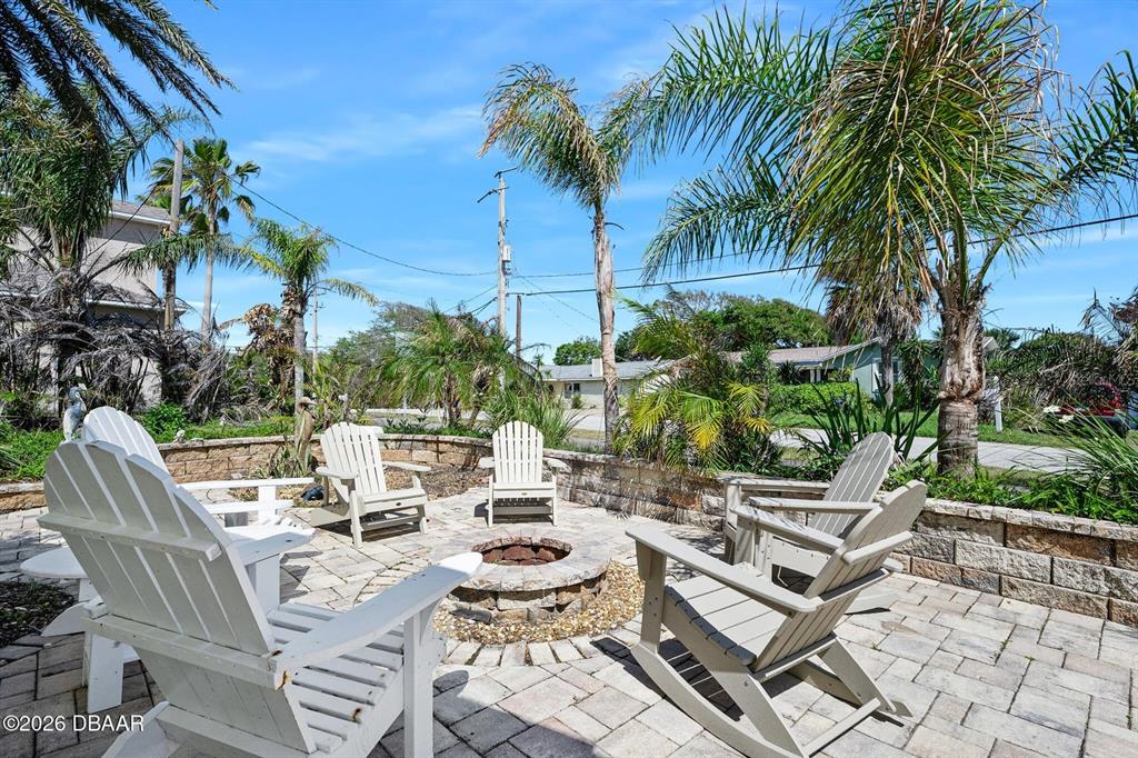 A stone patio features a fire pit surrounded by white Adirondack chairs and palm trees — 4708 DIXIE DRIVE, PONCE INLET, FL