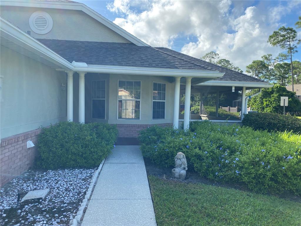 A concrete walkway leads to the covered front entrance of a house with a screened porch — 101 BRAEBURN CIRCLE, DAYTONA BEACH, FL