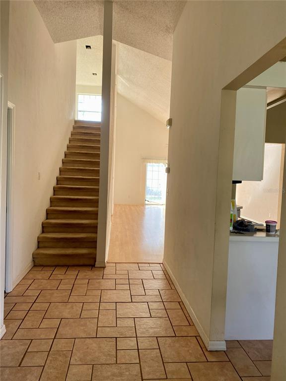A tiled entryway leads to a carpeted staircase and an open living area with vaulted ceilings — 101 BRAEBURN CIRCLE, DAYTONA BEACH, FL