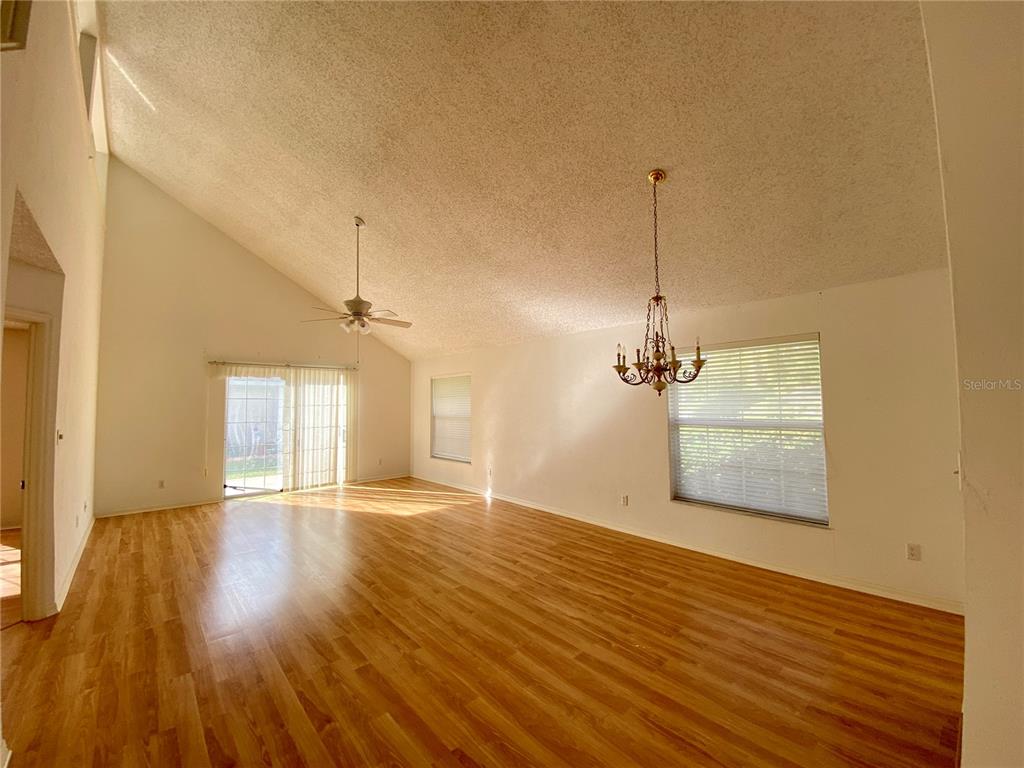 A living room with vaulted ceilings, wood-look flooring, a ceiling fan, and a chandelier — 101 BRAEBURN CIRCLE, DAYTONA BEACH, FL