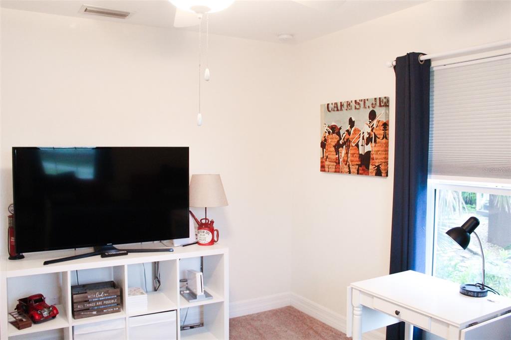A room features a television on a white storage unit, a desk, and wall art — 206 ANTILLA DRIVE, ROTONDA WEST, FL