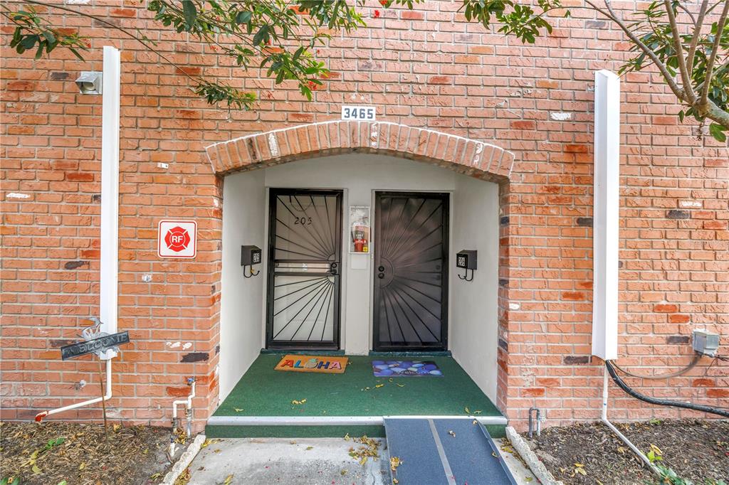 An exterior view shows two front doors with security gates under a brick archway — 3465 41ST TERRACE S UNIT 205, ST PETERSBURG, FL