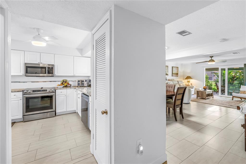 A white kitchen with stainless steel appliances opens into a living area with tile floors — 3465 41ST TERRACE S UNIT 205, ST PETERSBURG, FL