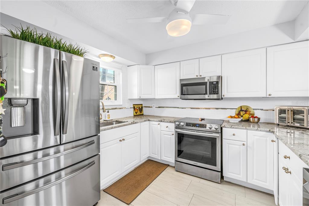 A kitchen with white cabinets, stainless steel appliances, granite countertops, and a ceiling fan — 3465 41ST TERRACE S UNIT 205, ST PETERSBURG, FL