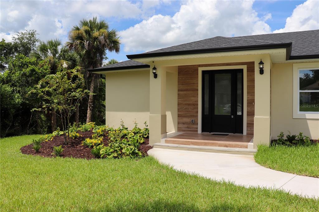 An aerial view of a single-story house with a garage, lawn, and surrounding trees — 4880 BARNA AVENUE, TITUSVILLE, FL