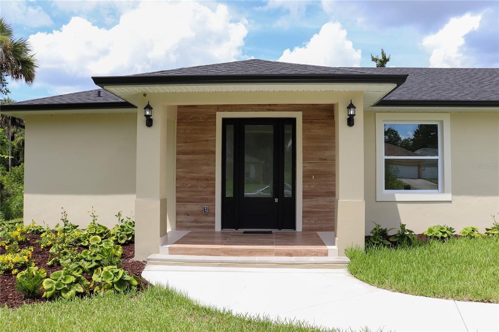A single-story house with a light-colored exterior, dark roof, and a front-facing garage — 4880 BARNA AVENUE, TITUSVILLE, FL