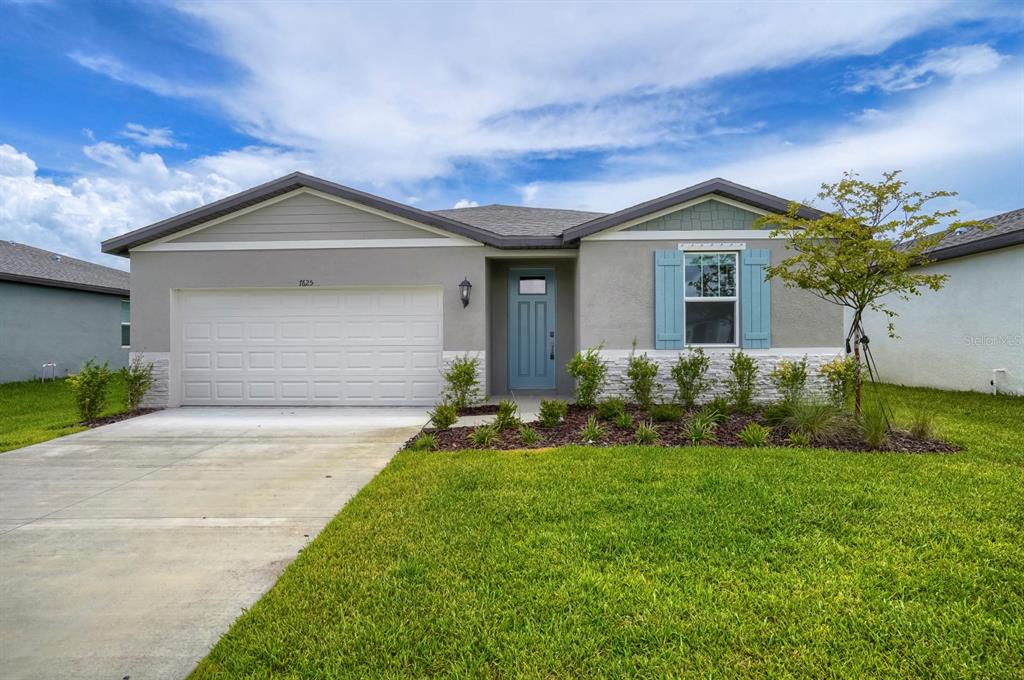 A single-story house with a gray stucco exterior, stone veneer, and a blue front door — 7625 SATTERFIELD TERRACE, PARRISH, FL