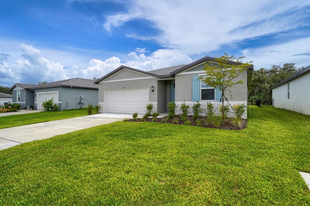 A single-story house with a white garage, gray siding, and a stone-veneer base — 7625 SATTERFIELD TERRACE, PARRISH, FL