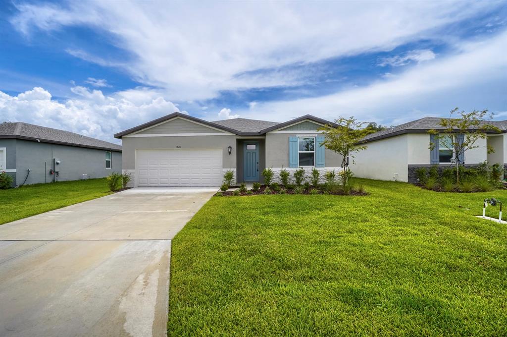 A single-story suburban house with a gray exterior, white garage door, and a blue front door — 7625 SATTERFIELD TERRACE, PARRISH, FL