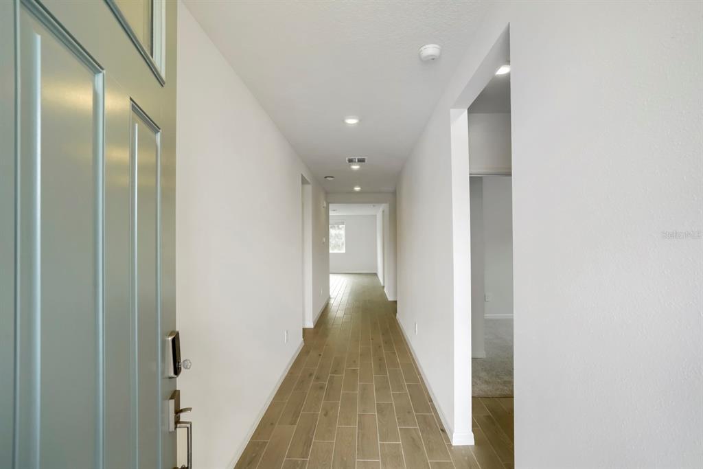 A view from an open doorway looking down a hallway with wood-look tile flooring — 7625 SATTERFIELD TERRACE, PARRISH, FL