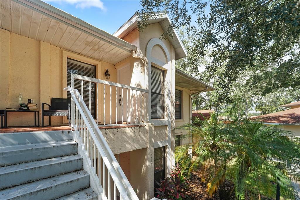 An exterior view of a two-story building with a staircase leading to an upper balcony — 317 KNOTTWOOD COURT UNIT 317, SUN CITY CENTER, FL