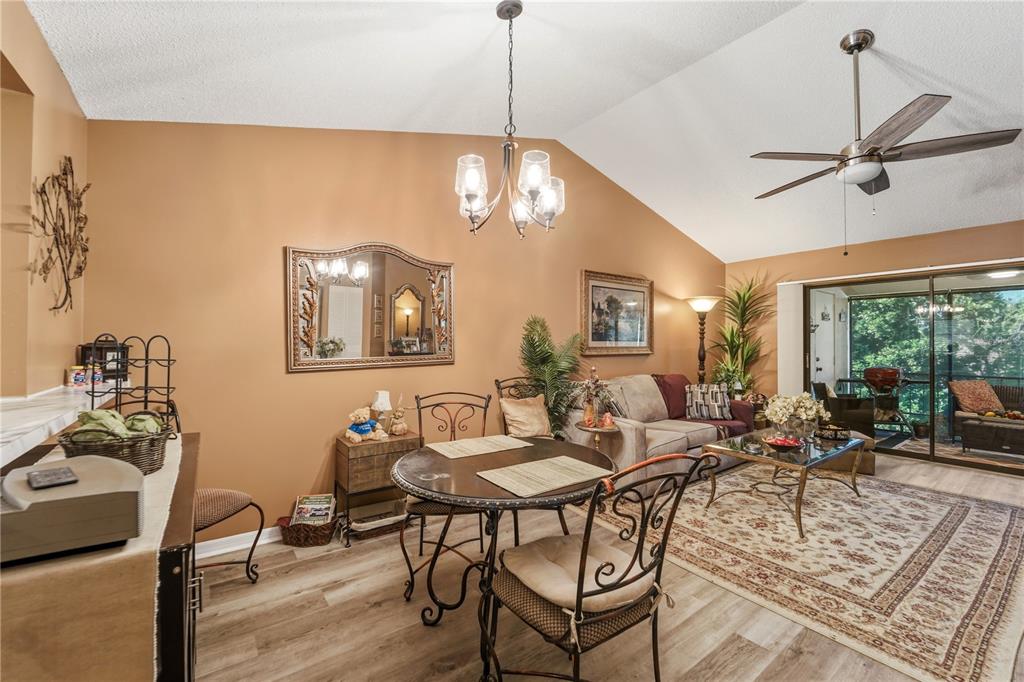 A dining and living area with vaulted ceilings, wood-look flooring, and a sliding glass door — 317 KNOTTWOOD COURT UNIT 317, SUN CITY CENTER, FL