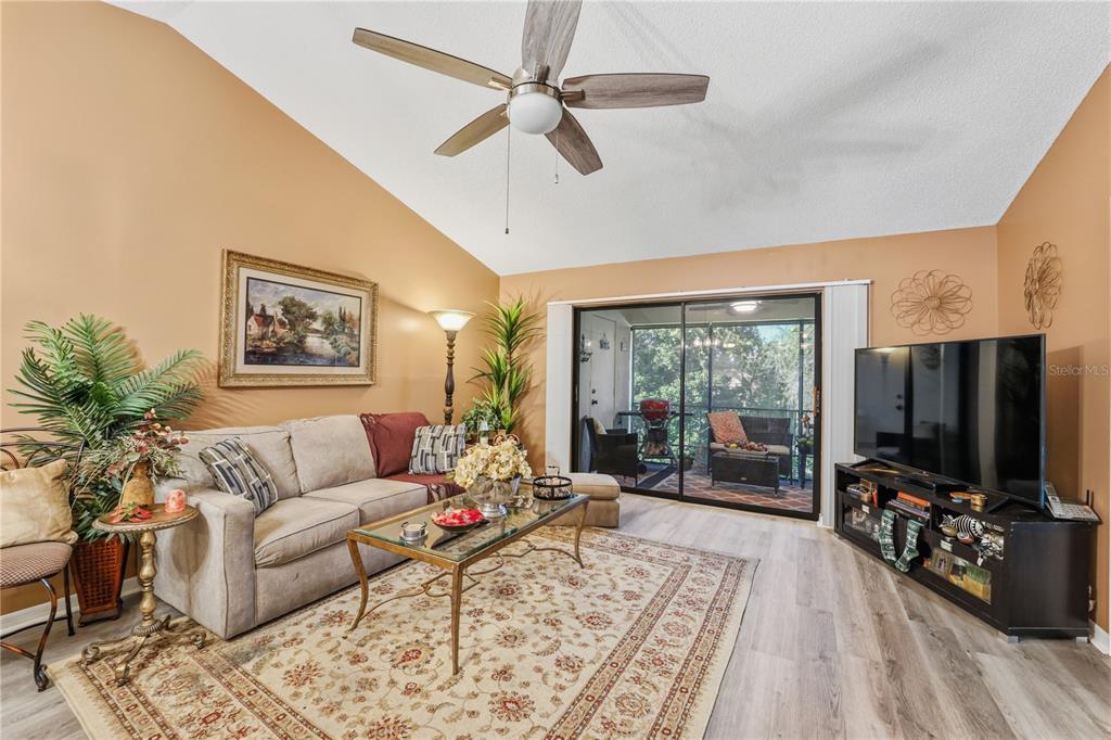 A living room features a beige sofa, a glass coffee table, and a sliding glass door — 317 KNOTTWOOD COURT UNIT 317, SUN CITY CENTER, FL
