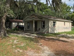 A single-story house with a covered front porch and a detached garage in the background — 1605 ROSE LANE, EUSTIS, FL