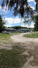 A dirt driveway leads toward several single-story houses under a large, moss-covered tree — 1605 ROSE LANE, EUSTIS, FL