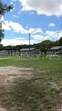 A grassy yard leads to a row of single-story residential buildings under a blue sky — 1605 ROSE LANE, EUSTIS, FL