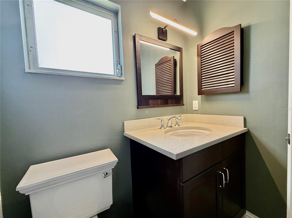 A bathroom features a dark wood vanity with a light countertop, mirror, and louvered cabinet — 2217 HOPKINS DRIVE W UNIT 2217, BRADENTON, FL